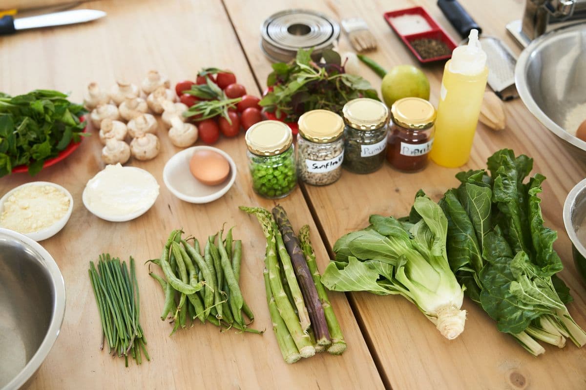 Fresh vegetables, herbs and spices laid out on a wooden table — budget-friendly healthy cooking ingredients