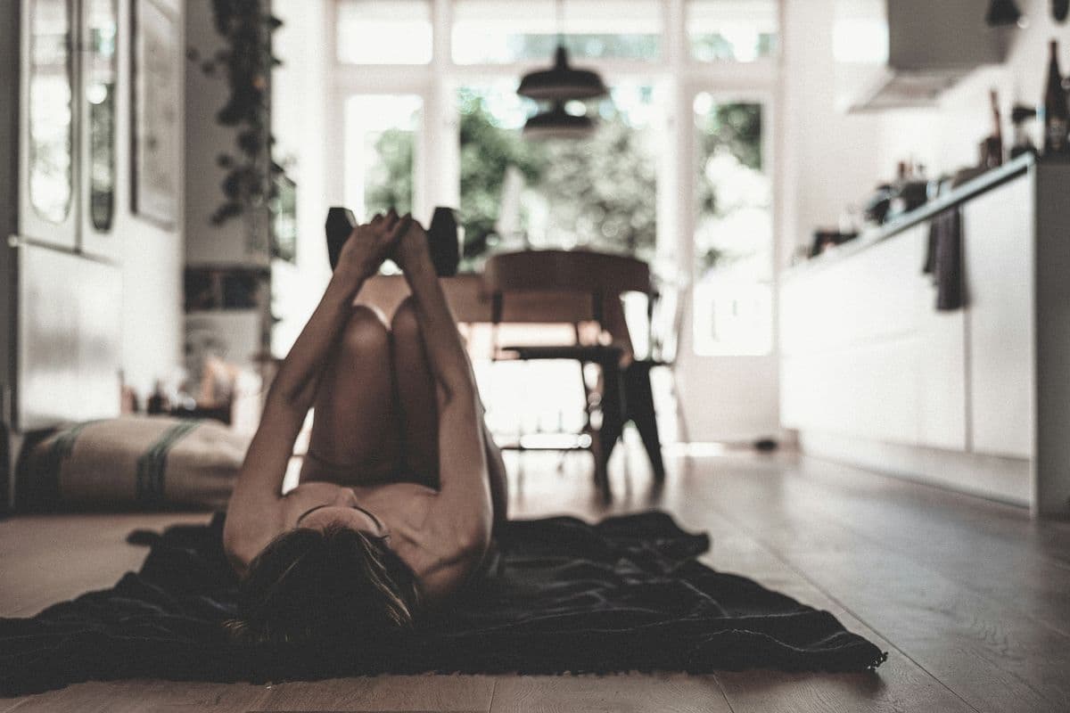 Person exercising with dumbbells on the floor at home — no gym needed for a busy parent workout