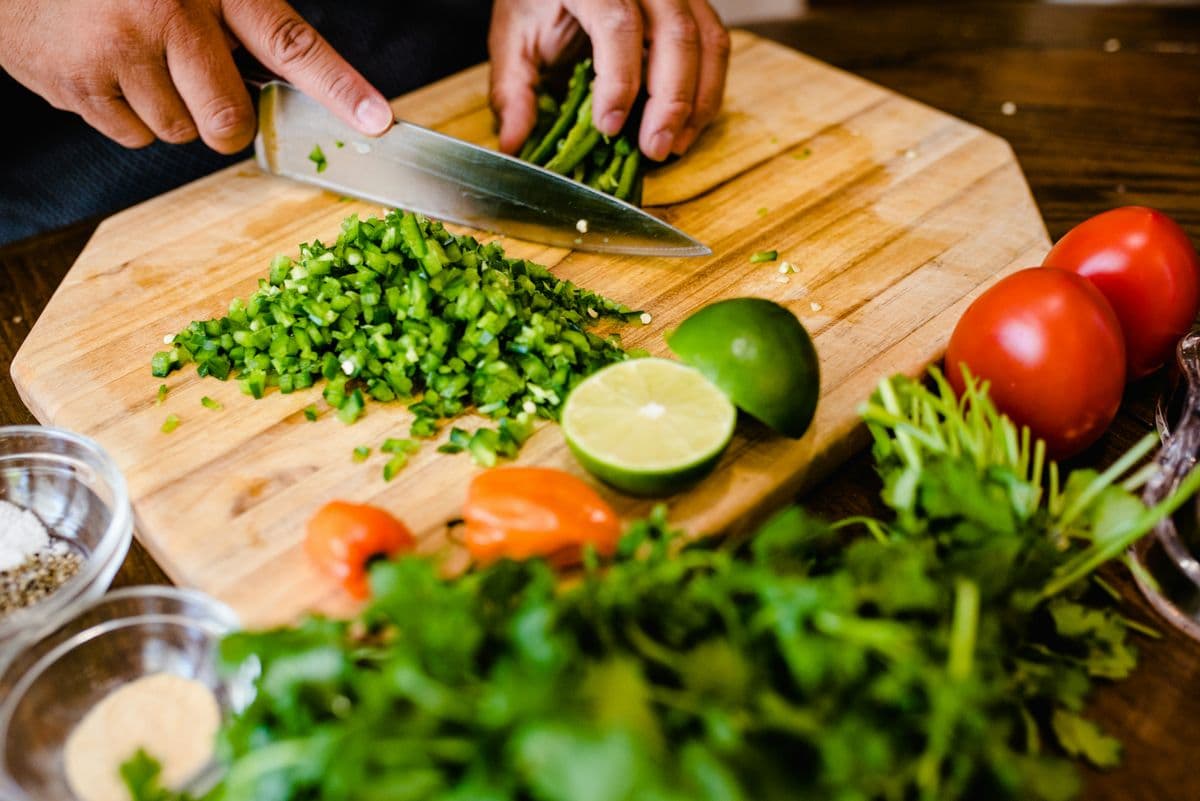 Chopping fresh peppers on a wooden board with lime and tomatoes for a quick high-protein dinner