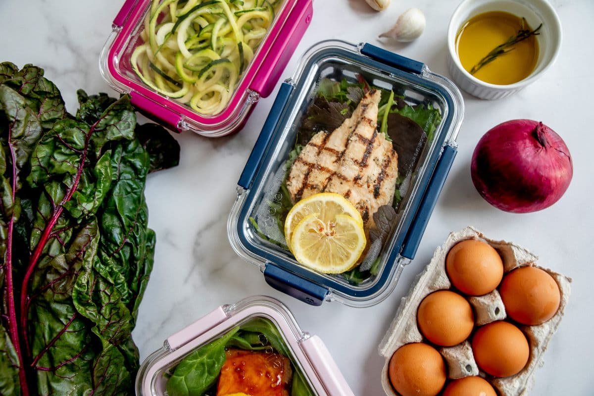 Glass meal prep containers with grilled chicken, greens and eggs — five days of packed lunches