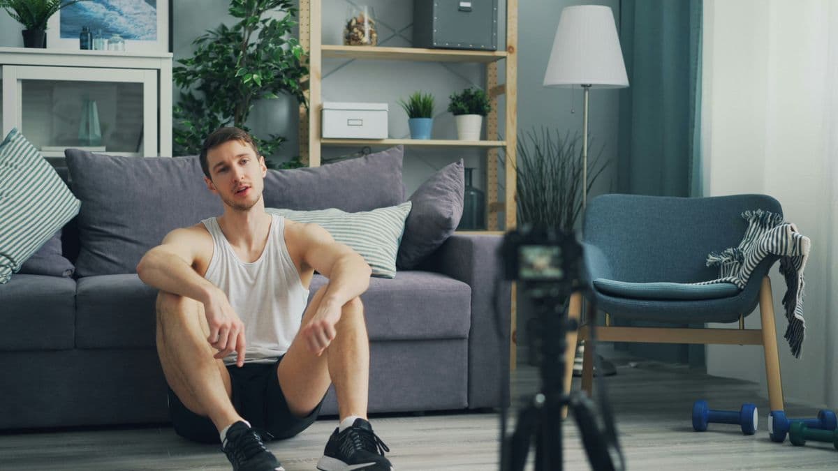 Man sitting on living room floor with dumbbells during a bodyweight workout at home