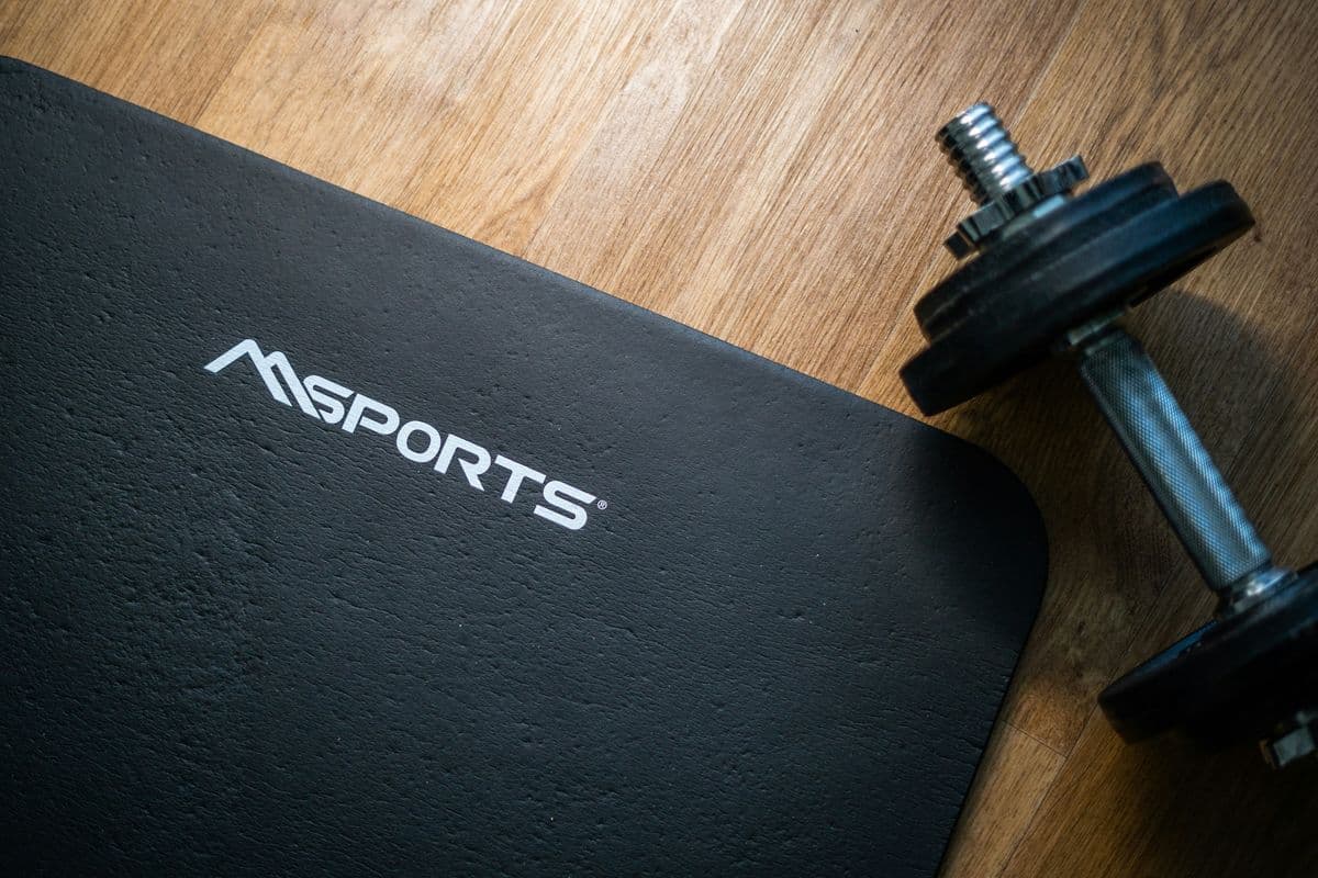 Exercise mat and dumbbell on a wooden floor — simple home setup for a 20-minute dumbbell workout