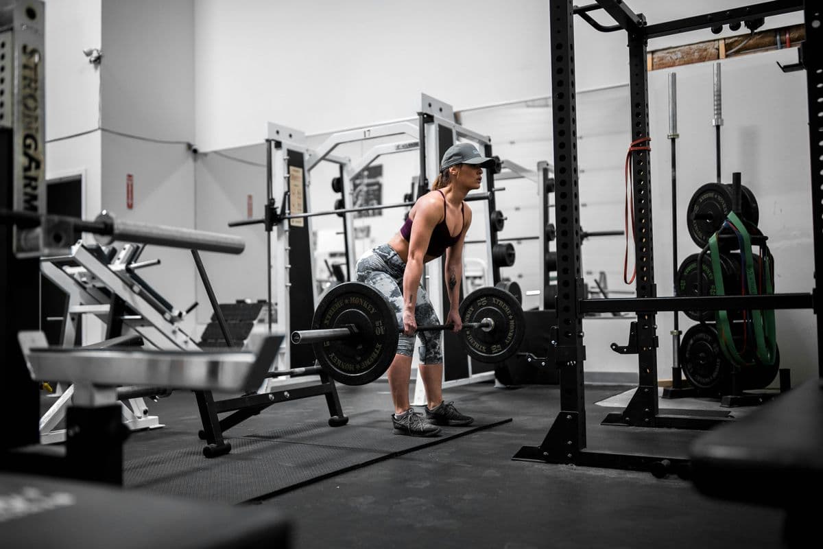 Woman performing a barbell deadlift in a gym — losing weight through strength training without counting calories